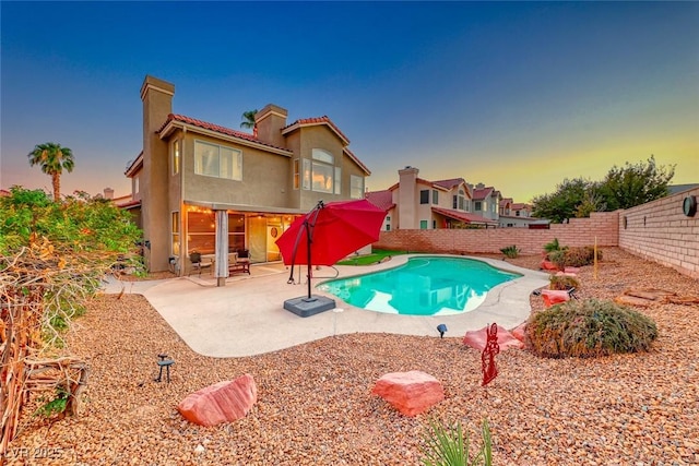 pool at dusk with a patio area and a fenced backyard