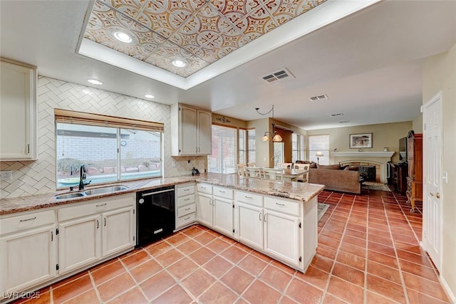 kitchen with visible vents, a peninsula, a sink, dishwasher, and a raised ceiling