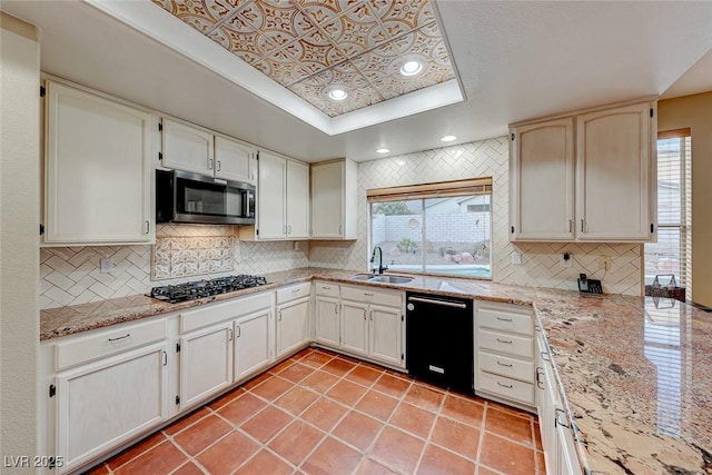 kitchen featuring stainless steel microwave, black dishwasher, gas stovetop, a raised ceiling, and a sink