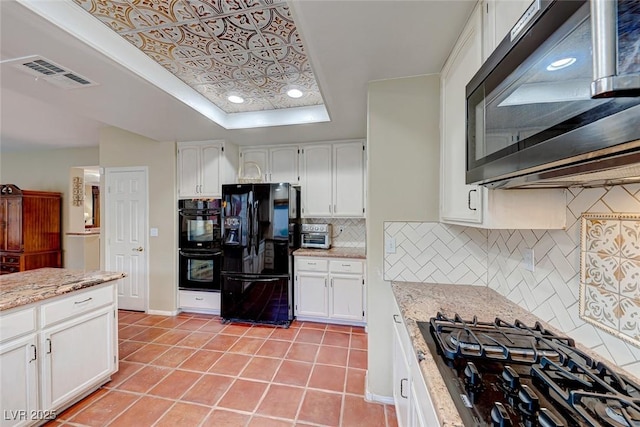 kitchen with visible vents, light tile patterned floors, light stone counters, white cabinets, and black appliances