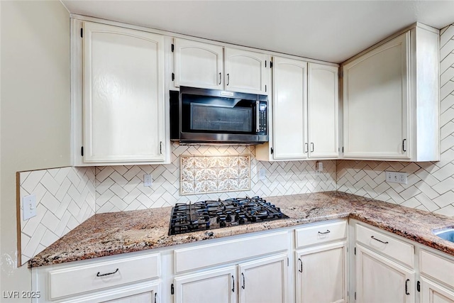 kitchen featuring decorative backsplash, white cabinetry, black gas stovetop, and light stone countertops