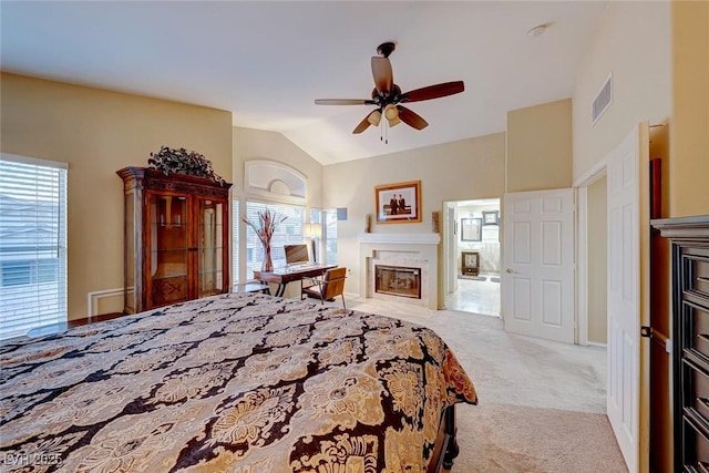 bedroom with visible vents, light carpet, a high end fireplace, and vaulted ceiling