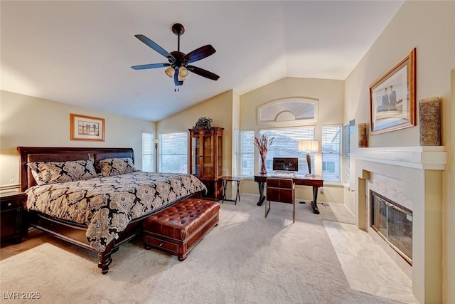 bedroom featuring lofted ceiling, a high end fireplace, baseboards, light colored carpet, and ceiling fan