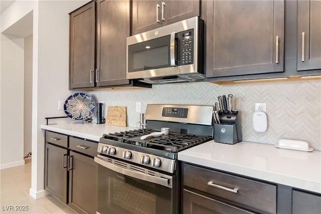 kitchen with decorative backsplash, light countertops, dark brown cabinetry, and stainless steel appliances