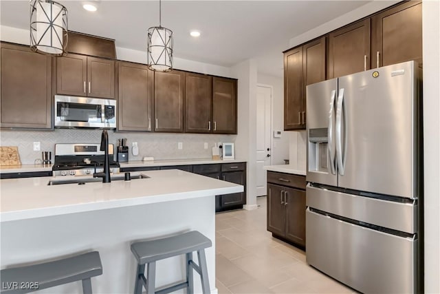 kitchen with dark brown cabinets, decorative backsplash, appliances with stainless steel finishes, and light countertops