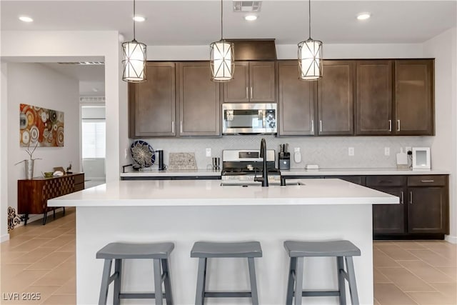 kitchen featuring stainless steel appliances, dark brown cabinetry, visible vents, and light countertops