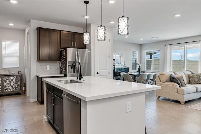 kitchen with backsplash, open floor plan, light countertops, appliances with stainless steel finishes, and a sink