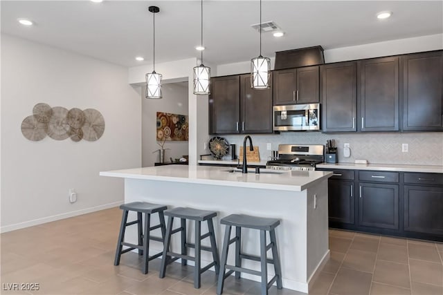 kitchen with backsplash, visible vents, a breakfast bar area, and stainless steel appliances