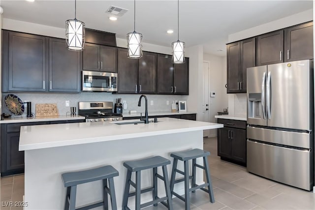 kitchen with tasteful backsplash, dark brown cabinetry, stainless steel appliances, and a sink