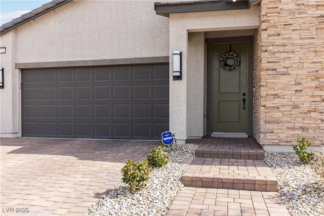 property entrance featuring stone siding, stucco siding, and decorative driveway