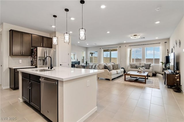 kitchen featuring stainless steel fridge with ice dispenser, a sink, light countertops, dark brown cabinets, and open floor plan