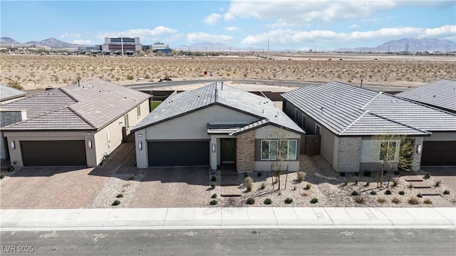 single story home with view of desert, an attached garage, a mountain view, and stucco siding