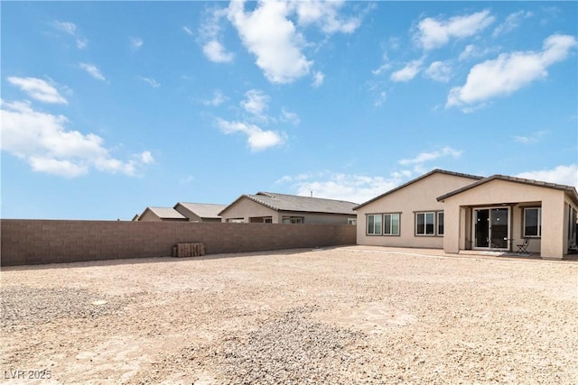 rear view of property featuring stucco siding and a fenced backyard