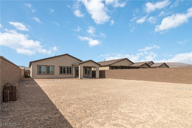 rear view of house featuring a fenced backyard and stucco siding