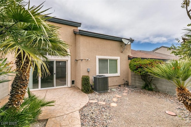 rear view of property with a patio area, central AC unit, and stucco siding