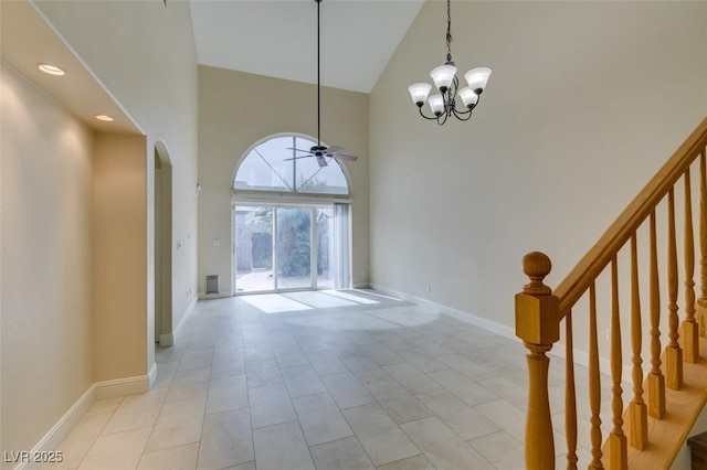 entrance foyer featuring stairway, baseboards, high vaulted ceiling, arched walkways, and ceiling fan with notable chandelier