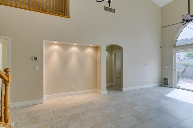 spare room with visible vents, arched walkways, a towering ceiling, and a ceiling fan