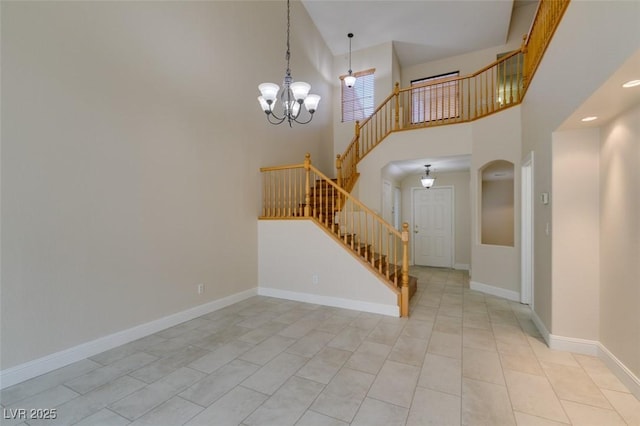 interior space featuring baseboards, a high ceiling, and an inviting chandelier