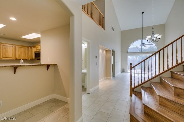 stairway with visible vents, baseboards, a chandelier, a high ceiling, and arched walkways