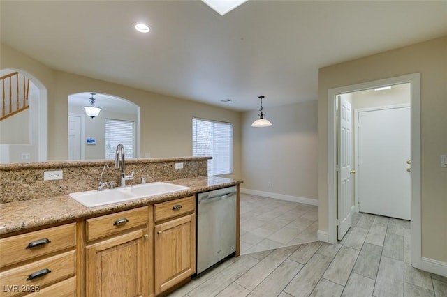 kitchen with dishwasher, pendant lighting, light countertops, arched walkways, and a sink