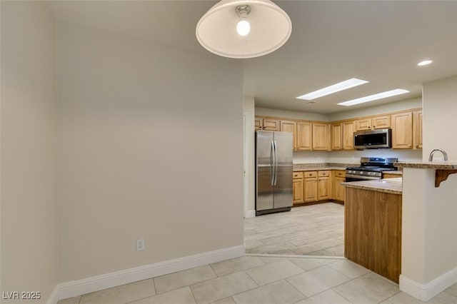 kitchen featuring light tile patterned floors, baseboards, a peninsula, a sink, and stainless steel appliances