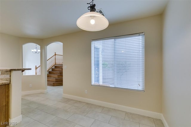 spare room with visible vents, baseboards, light tile patterned flooring, arched walkways, and stairs