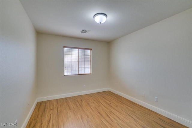 unfurnished room with light wood-type flooring, visible vents, and baseboards