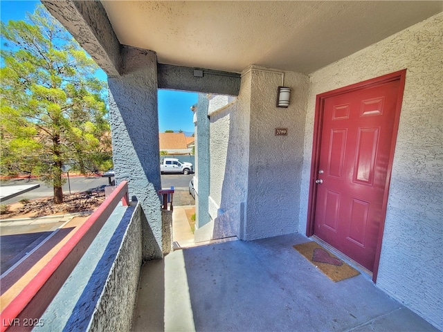 view of exterior entry with a balcony and stucco siding