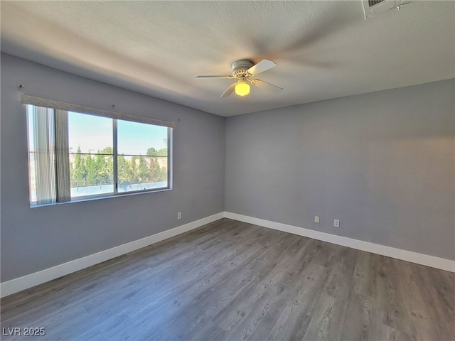 empty room featuring dark wood finished floors, baseboards, and ceiling fan