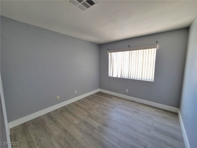 unfurnished room featuring visible vents, baseboards, and wood finished floors