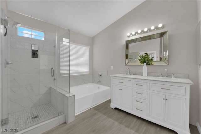 bathroom featuring double vanity, a stall shower, a garden tub, and a sink