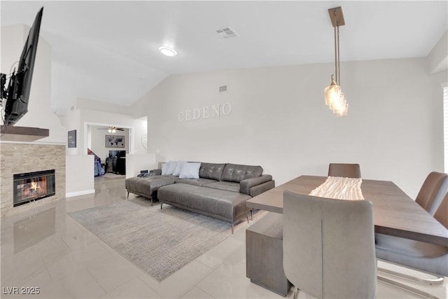 living area featuring visible vents, lofted ceiling, and a glass covered fireplace