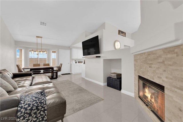 living area with light tile patterned floors, visible vents, baseboards, a fireplace, and a notable chandelier