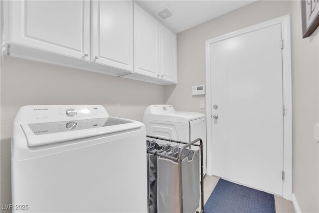 laundry area with washer and clothes dryer, visible vents, and cabinet space