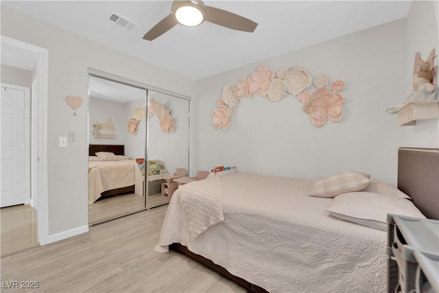 bedroom featuring a ceiling fan, visible vents, light wood finished floors, baseboards, and a closet