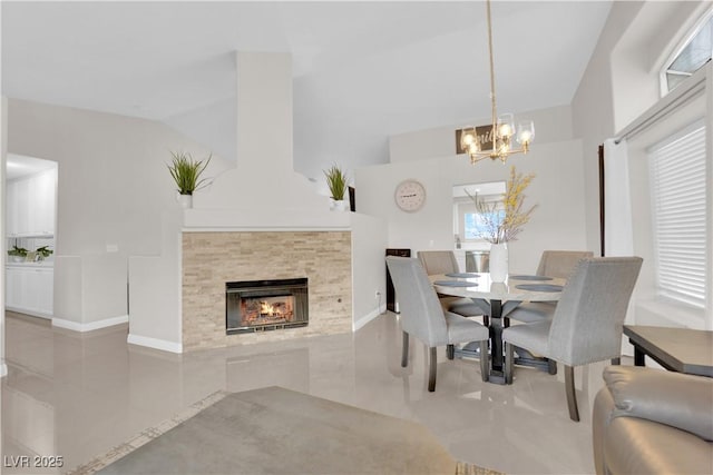 dining space featuring vaulted ceiling, baseboards, a tile fireplace, and a chandelier