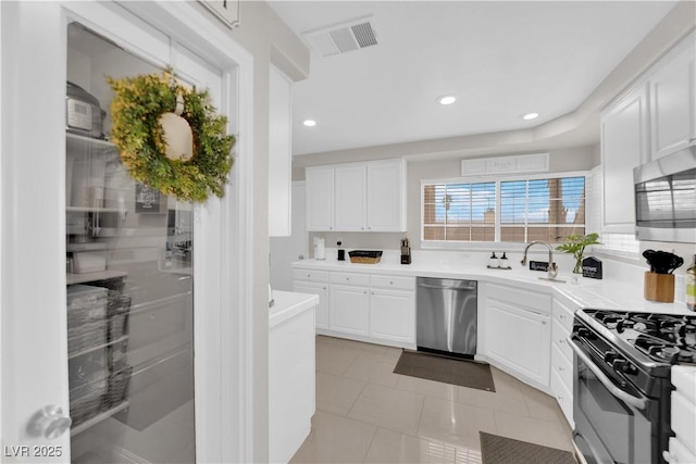 kitchen featuring visible vents, white cabinets, stainless steel appliances, and a sink