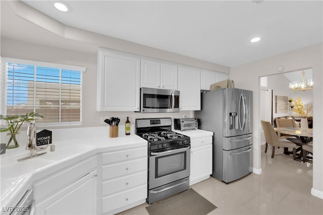 kitchen featuring recessed lighting, stainless steel appliances, an inviting chandelier, and white cabinets