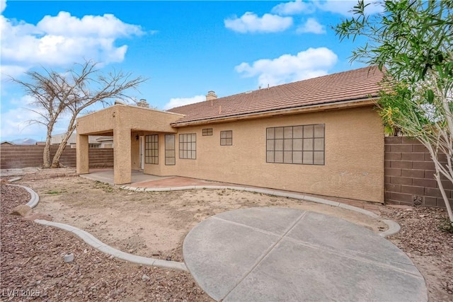 rear view of house with stucco siding, a patio, a fenced backyard, and a tiled roof