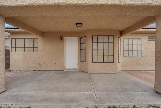 property entrance featuring stucco siding and a patio