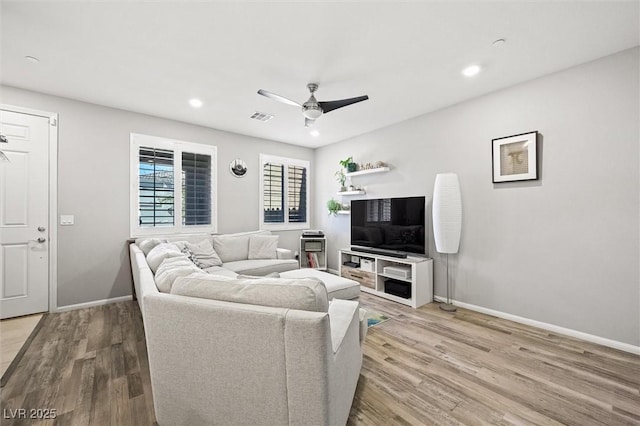 living area featuring a ceiling fan, wood finished floors, visible vents, and baseboards