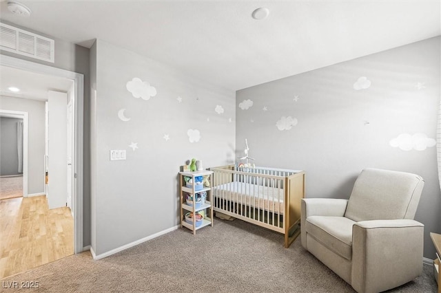 carpeted bedroom with visible vents, a crib, and baseboards