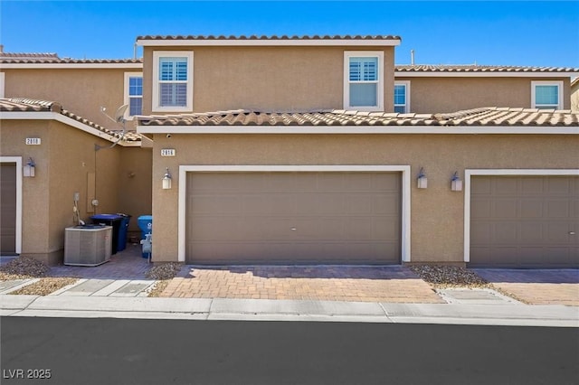 multi unit property featuring a tile roof, a garage, driveway, and stucco siding