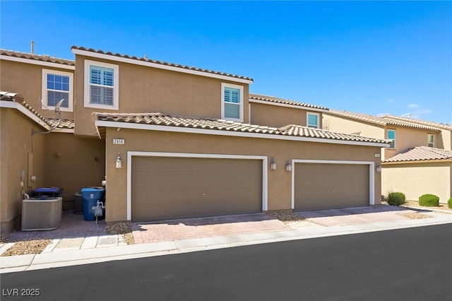 view of front of home with a tile roof, a garage, and stucco siding