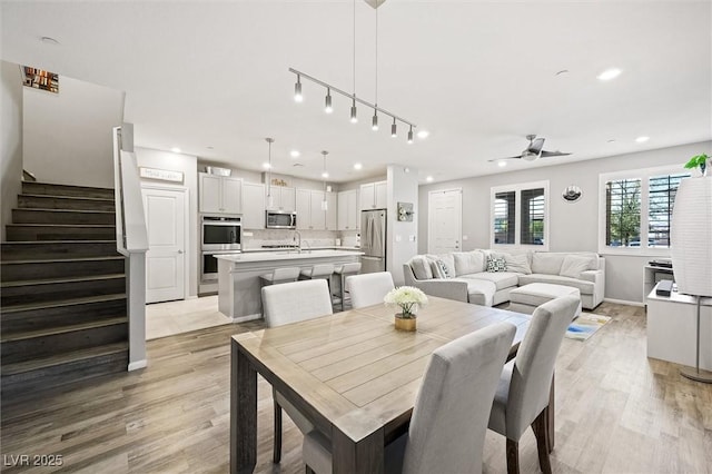 dining space featuring baseboards, ceiling fan, stairs, light wood-type flooring, and recessed lighting