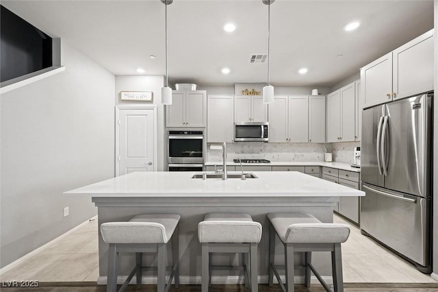 kitchen featuring visible vents, decorative backsplash, light tile patterned flooring, stainless steel appliances, and a sink