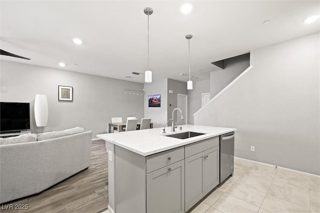 kitchen featuring gray cabinetry, a sink, open floor plan, light countertops, and dishwasher