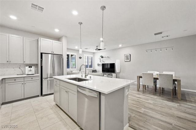 kitchen with visible vents, a sink, decorative light fixtures, appliances with stainless steel finishes, and light countertops