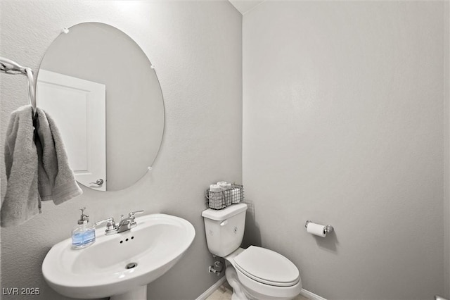 half bath featuring a sink, baseboards, and toilet