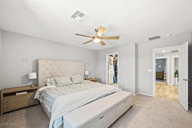 bedroom with visible vents, baseboards, light colored carpet, and a spacious closet